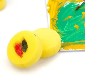 Primo piano di spugne da pittura rotonde gialle con macchie di colore per bambini.