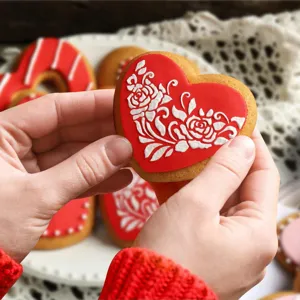 Close up of decorated heart shaped cookie with white rose icing, perfect baking inspiration.