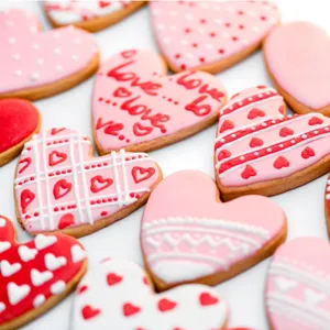 Close-up view of beautifully decorated heart-shaped cookies with pink icing and sweet love patterns.