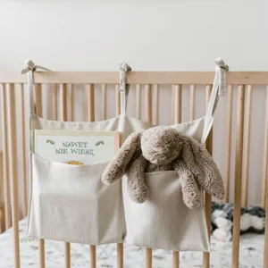 Detail view of linen baby crib hanging storage bag with double pockets and ties in nursery.