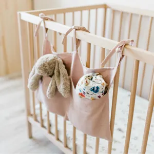 Linen baby crib hanging organizer with double pockets, nursery storage bag for diapers and toys.