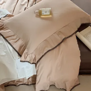 Solid color cotton bedding set with ruffled edge and dark piping, elegant bedroom lifestyle view.