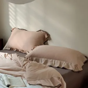 Ruffle bedding set detail shot, soft pink duvet cover and pillowcases with dark brown edge.