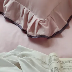 Pink cotton bedding detail view, solid color duvet cover with purple ruffled edge trim.