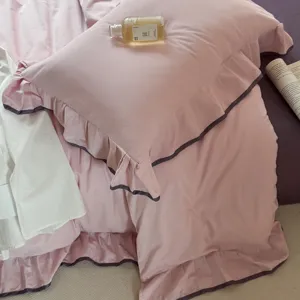Detailed view of pink cotton bedding set with dark ruffles, soft and cozy bedroom scene.