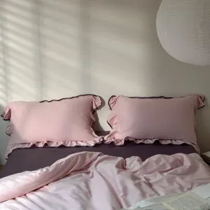 Close-up detail of pink ruffled pillowcase and bedding set in cozy bedroom scene.