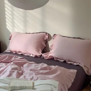 A chic pink ruffle duvet cover and dark purple bed sheet bedding detail view