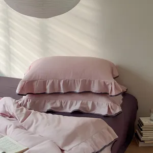 Pink cotton bedding set with elegant ruffled edges, soft duvet cover and pillowcases for cozy room.