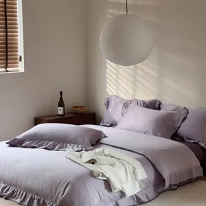 Detailed shot of purple cotton bedding set with elegant ruffled edge design in cozy bedroom.