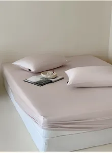 Rosa seidenartiges Spannbetttuch Detailaufnahme mit minimalistischem Schlafzimmer.