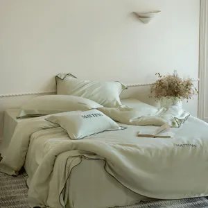 Detailed shot of luxurious washed Tencel bedding set, smooth solid green fabric with black piping.