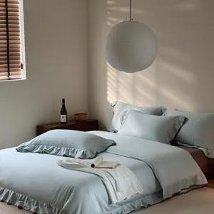 Detail view of light blue cotton bedding set with delicate ruffles displayed in cozy bedroom.