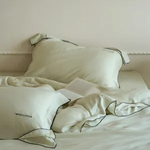 Luxurious sand-washed tencel bedding set with elegant black piping and solid green color.