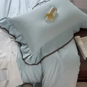 Detail shot of light blue bedding set featuring elegant dark brown ruffle pillowcase.