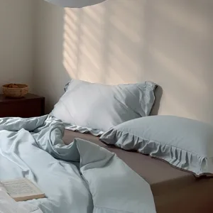Close up detail of light blue ruffled cotton bedding set in a cozy minimalist bedroom.