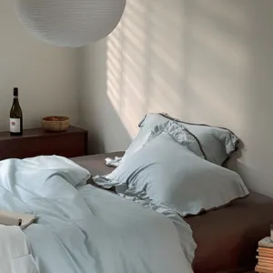 Cozy bedroom scene showing details of light blue cotton ruffled bedding set and pillows.