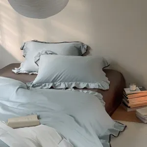 Cotton bedding set detail view, featuring light blue ruffled duvet cover and matching pillowcases.