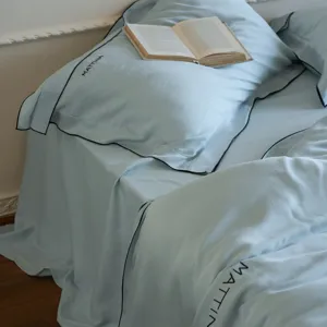 Luxury light blue Tencel duvet cover set with elegant black piping and delicate embroidery details.