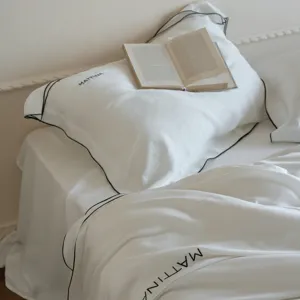 Exquisite detail of white lyocell bedding with elegant black piping and minimalist style.
