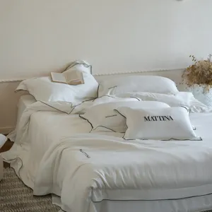 Detailed view of white silk-feel lyocell bedding set with elegant black border and embroidery.