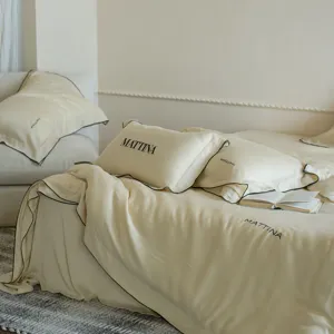 Detail view of luxury silk-like lyocell bedding in elegant beige with black piping and brand print.