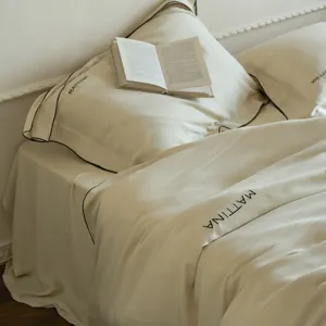 Luxurious Tencel bedding set in solid beige with black contrast piping and elegant embroidery details.