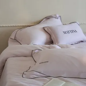 Luxurious pink tencel bedding set with black piping and elegant embroidery for bedroom decor.