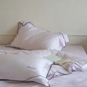 Close-up detail of soft pink lyocell bedding set with elegant black piping and embroidery.