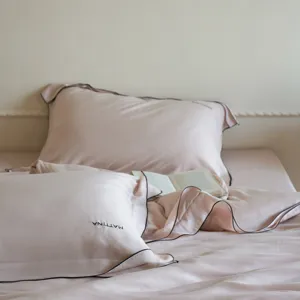 Pink lyocell silk bedding detail shot, smooth texture, elegant solid color design.