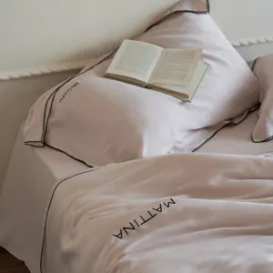 Detail shot of luxury washed tencel bedding set in soft pink with elegant black trim.