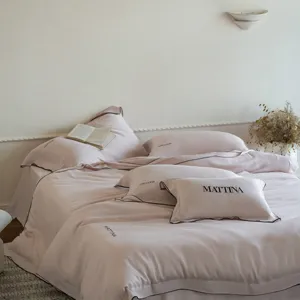 Luxurious tencel bedding set detail view with elegant black piping and soft pink fabric.