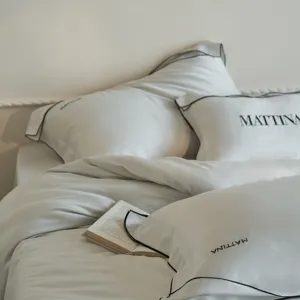 Detailed shot of luxury light grey Tencel bedding set with elegant black piping and pillow detail.