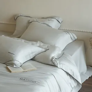 Detail shot of luxury tencel bedding set with black piped edges and delicate embroidery.