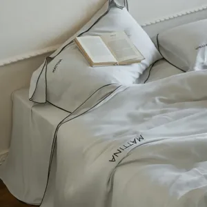 Luxury silky Tencel bed linen detail, smooth lyocell fabric with elegant black piping trim.