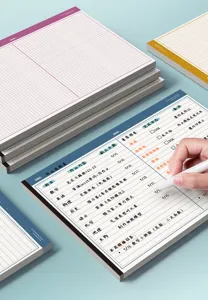 Vista de cerca de un bloc de notas cuadriculado B5 con diseño de planificador y bolígrafo.