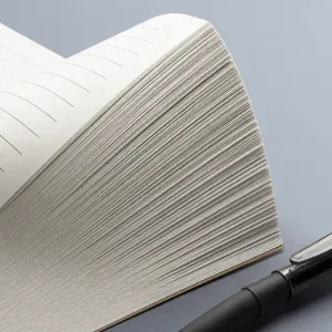 Portable pocket lined notebook with thick pages, close-up side view showing paper texture.