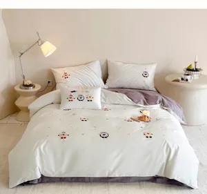Detailopname van geborduurd katoenen beddengoed met schattige motieven in knusse slaapkamer.