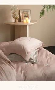 Vue détaillée de la housse de couette en coton Tencel rose avec broderie de papillons.