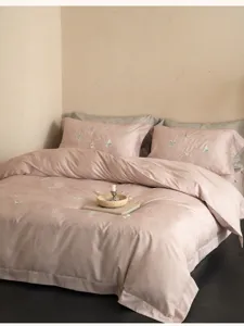 Gros plan sur la broderie de papillons délicats sur du linge de lit rose, ambiance cosy.