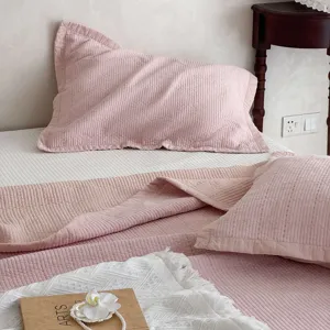 Rosa gesteppte Baumwoll-Tagesdecke Detail zeigt weiche Textur und gemütliches Schlafzimmer.