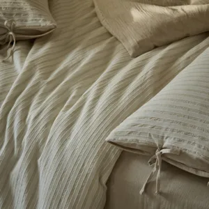 Parure de lit en coton lavé et lin avec rayures texturées et nouons, ambiance chaleureuse.