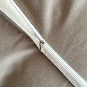 Detailed shot of premium taupe bedding duvet cover with clean white zipper and hardware.