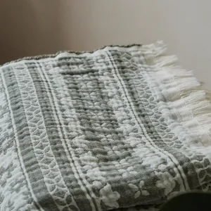 Retro cotton jacquard throw blanket detail, vintage green fringe sofa blanket texture.