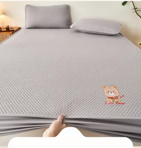 Vista dettagliata del coprimaterasso testurato grigio con ricamo di un orsetto carino.