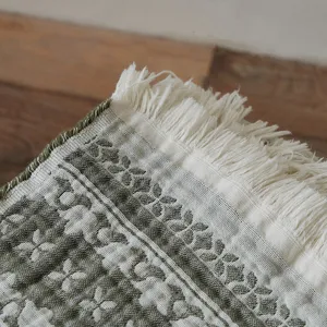 Close-up detail of vintage cotton jacquard throw blanket showing fine fringe and pattern.
