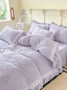 Detalle de ropa de cama de terciopelo de leche lavanda con patrón floral y encaje blanco delicado.