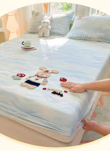 Soft cotton fitted sheet detail with cute rabbit embroidery and cozy blue water wave pattern.