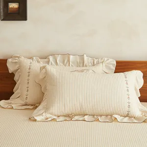 Vue de détail d'un ensemble de literie beige en coton avec broderie florale.