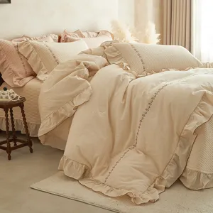 Vue détaillée d'une parure de lit en coton et lin brodée de fleurs avec des volants.