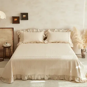 Vue détail de couvre-lit matelassé en coton et lin beige avec délicate broderie florale.